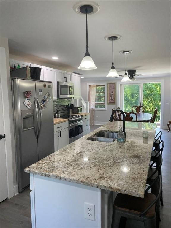 16562 Ridge Rd, Murray, NY 14470 - kitchen with appliances with stainless steel finishes, white cabinetry, ceiling fan, and backsplash