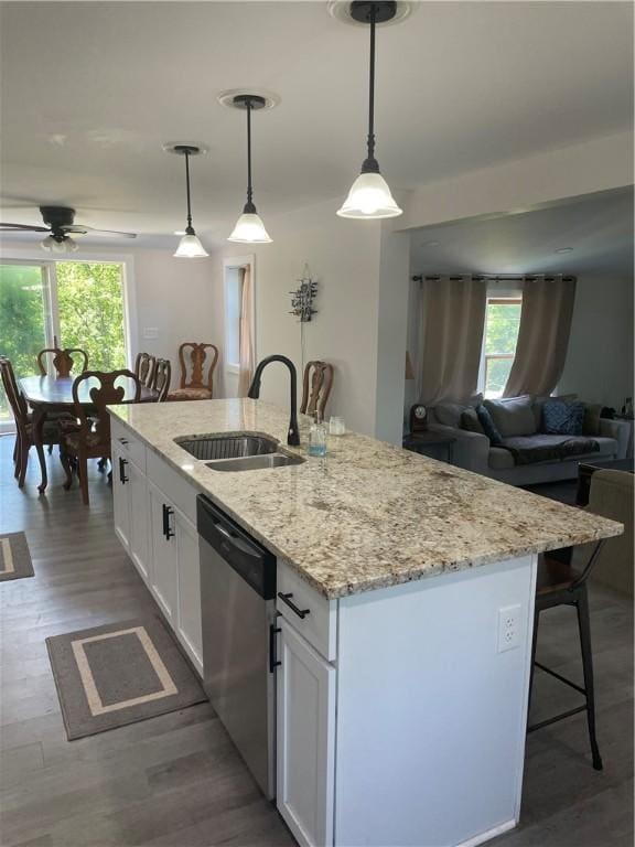 16562 Ridge Rd, Murray, NY 14470 - kitchen with stainless steel dishwasher, an island with sink, ceiling fan, a breakfast bar, and white cabinets