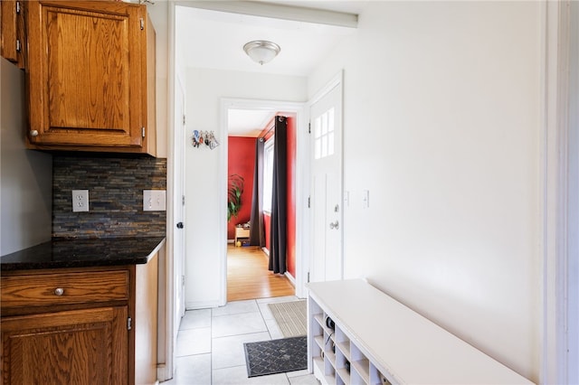 304 Simpson Rd, Irondequoit, NY 14617 - kitchen with decorative backsplash, light tile patterned floors, brown cabinetry, and dark countertops