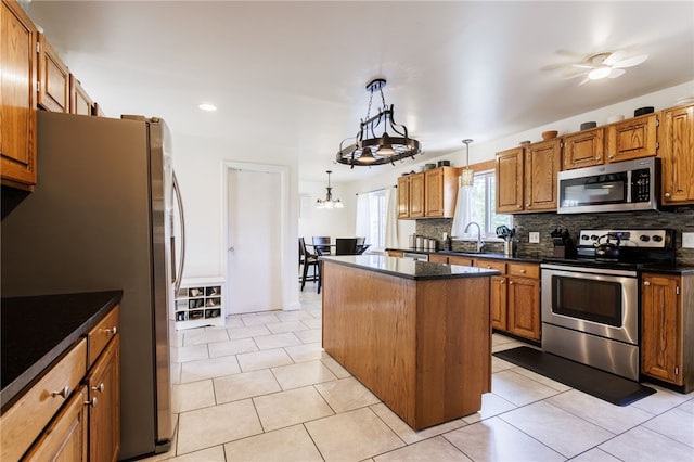 304 Simpson Rd, Irondequoit, NY 14617 - kitchen with appliances with stainless steel finishes, a center island, dark countertops, backsplash, and brown cabinetry