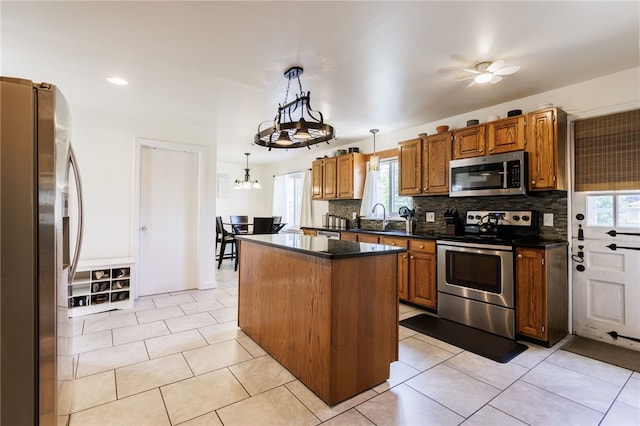 304 Simpson Rd, Irondequoit, NY 14617 - kitchen with stainless steel appliances, dark countertops, a kitchen island, brown cabinets, and decorative backsplash