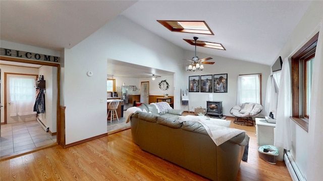 9447 County Route 75, Pulteney, NY 14418 - living room featuring a baseboard radiator, a wood stove, vaulted ceiling, healthy amount of natural light, and a skylight