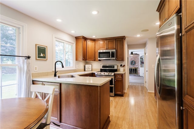 7 Chipping Rdg, Perinton, NY 14450 - kitchen with stainless steel appliances, a peninsula, light wood-style floors, light countertops, and brown cabinetry