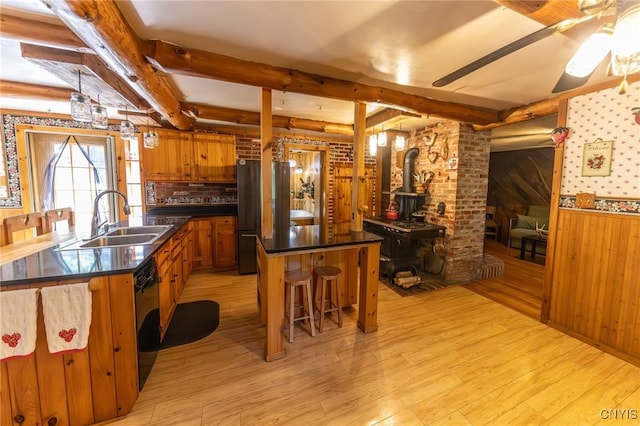 7940 Soft Maple Rd, New Bremen, NY 13327 - kitchen with a wood stove, light wood-style floors, brown cabinets, beam ceiling, and dark countertops