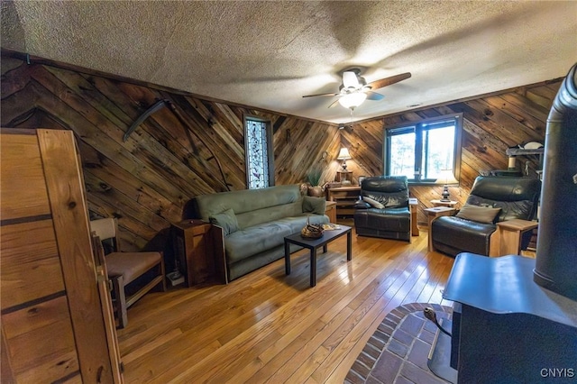 7940 Soft Maple Rd, New Bremen, NY 13327 - living area featuring a ceiling fan, wooden walls, hardwood / wood-style flooring, and a textured ceiling