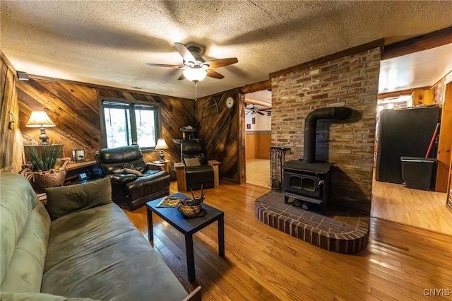 7940 Soft Maple Rd, New Bremen, NY 13327 - living area with wood walls, a ceiling fan, a wood stove, a textured ceiling, and hardwood / wood-style floors