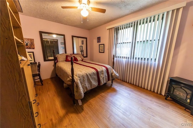 7940 Soft Maple Rd, New Bremen, NY 13327 - bedroom featuring a wood stove, wood finished floors, a textured ceiling, and ceiling fan