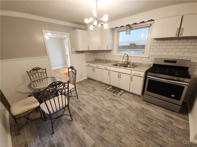 201 Jane Dr, Camillus, NY 13219 - kitchen with stainless steel gas range, light countertops, a chandelier, white cabinets, and ornamental molding