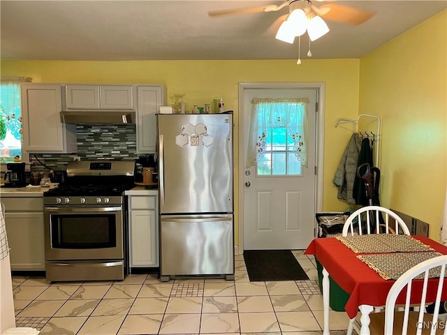 520 Seneca St, Fulton, NY 13069 - kitchen with appliances with stainless steel finishes, a ceiling fan, light marble finish flooring, tasteful backsplash, and under cabinet range hood