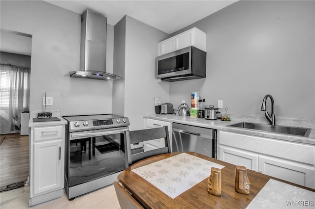 245 Tacoma Ave, Buffalo, NY 14216 - kitchen featuring appliances with stainless steel finishes, wall chimney range hood, white cabinets, and light countertops
