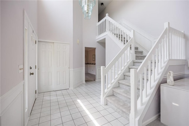 47 Edenfield Rd, Penfield, NY 14526 - entrance foyer with a high ceiling, stairs, a decorative wall, light tile patterned floors, and wainscoting