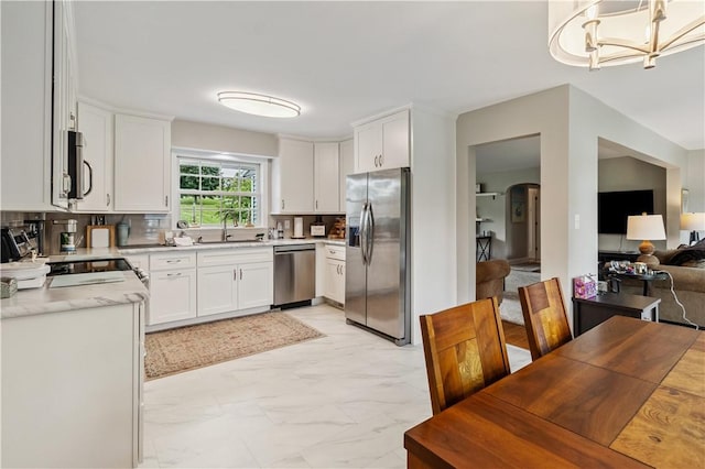 82 Rt 54 E Lake Rd, Milo, NY 14527 - kitchen featuring appliances with stainless steel finishes, light marble finish floors, white cabinetry, a chandelier, and arched walkways
