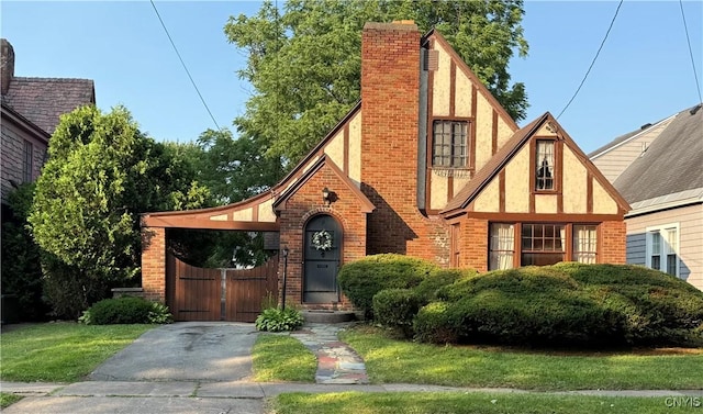 11 Brookline Dr, Utica, NY 13501 - english style home featuring stucco siding, brick siding, a chimney, and a gate