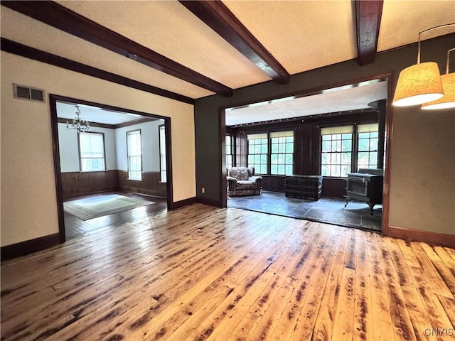 1765 W Rd, Oneida, NY 13421 - unfurnished living room with a wood stove, wood-type flooring, beam ceiling, and a chandelier