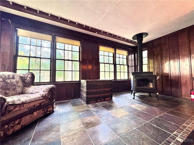 1765 W Rd, Oneida, NY 13421 - living area with a textured ceiling, plenty of natural light, wood walls, a wood stove, and stone tile floors