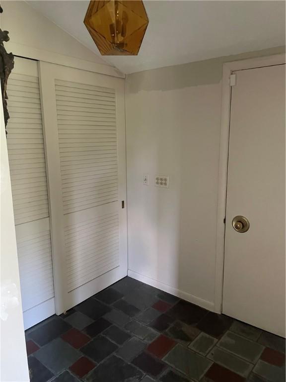 1077 Sharon Ct, Webster, NY 14580 - unfurnished bedroom featuring lofted ceiling, a closet, and dark stone finish floors