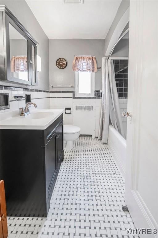 711 Colvin Blvd, Tonawanda, NY 14217 - bathroom featuring radiator heating unit, tile patterned floors, vanity, tile walls, and shower / bathtub combination with curtain