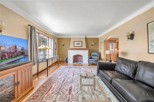 711 Colvin Blvd, Tonawanda, NY 14217 - living room with light wood finished floors, arched walkways, a brick fireplace, and crown molding