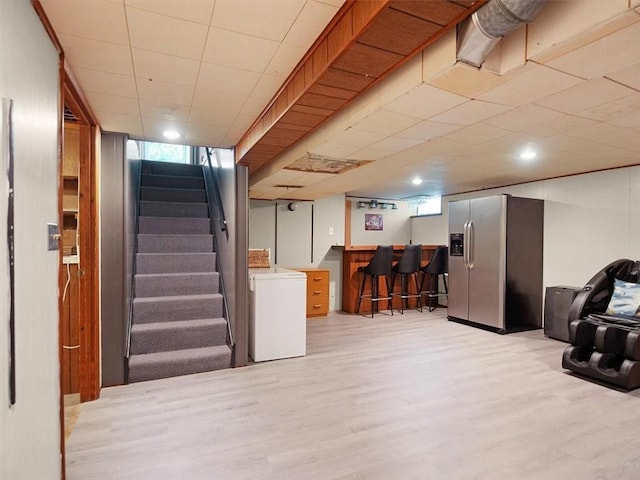 746 Dewitt Rd, Webster, NY 14580 - below grade area featuring stainless steel fridge, washer / dryer, a bar, stairway, and light wood-style flooring