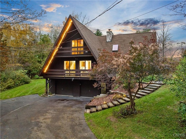 6139 Commane Rd, Lafayette, NY 13084 - a-frame style home featuring asphalt driveway, a balcony, a front yard, a garage, and a chimney
