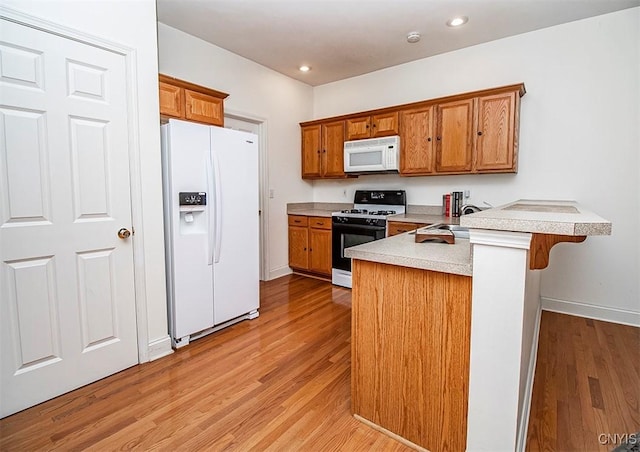 4203 Sandbar Ln, Clay, NY 13090 - kitchen featuring white appliances, a peninsula, brown cabinetry, light wood-style floors, and light countertops