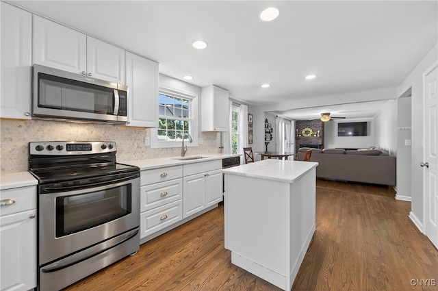 208 Single Dr, Clay, NY 13212 - kitchen featuring appliances with stainless steel finishes, decorative backsplash, a center island, light countertops, and dark wood-style flooring