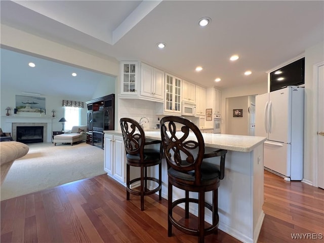 39 Wickendon Ct, Amherst, NY 14221 - kitchen featuring white appliances, dark wood-style flooring, white cabinetry, a kitchen breakfast bar, and glass insert cabinets