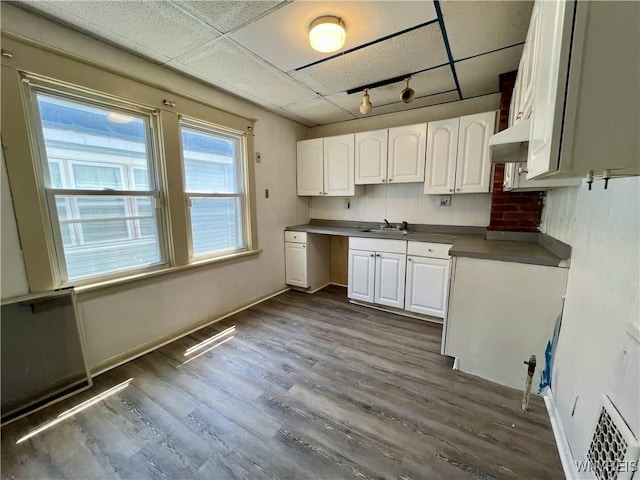 83 Andover Ave, Buffalo, NY 14215 - kitchen featuring dark wood-style floors, white cabinetry, track lighting, dark countertops, and a drop ceiling