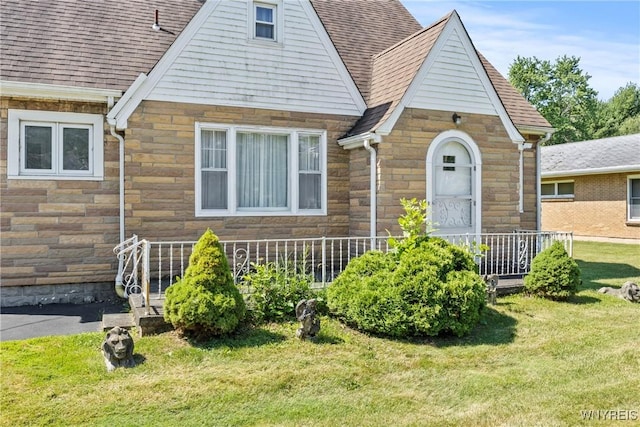 1419 Maple Rd, Amherst, NY 14221 - english style home featuring stone siding, a front yard, and roof with shingles