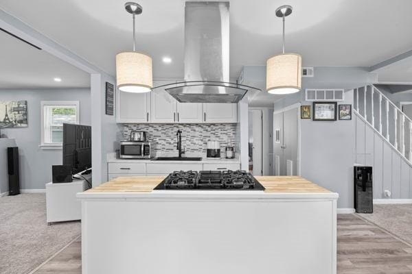 95 Ridgemar Rd, Greece, NY 14615 - kitchen featuring wall chimney exhaust hood, stainless steel microwave, black gas cooktop, white cabinets, and light wood-style flooring