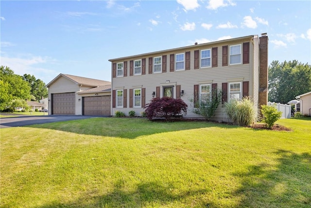 193 Orchard Creek Ln, Greece, NY 14612 - colonial house featuring asphalt driveway, a front yard, an attached garage, and a chimney
