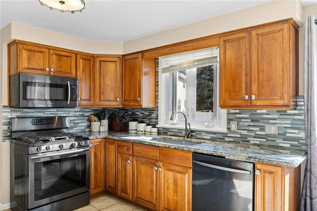 193 Orchard Creek Ln, Greece, NY 14612 - kitchen featuring stainless steel appliances, stone counters, brown cabinets, decorative backsplash, and light tile patterned floors
