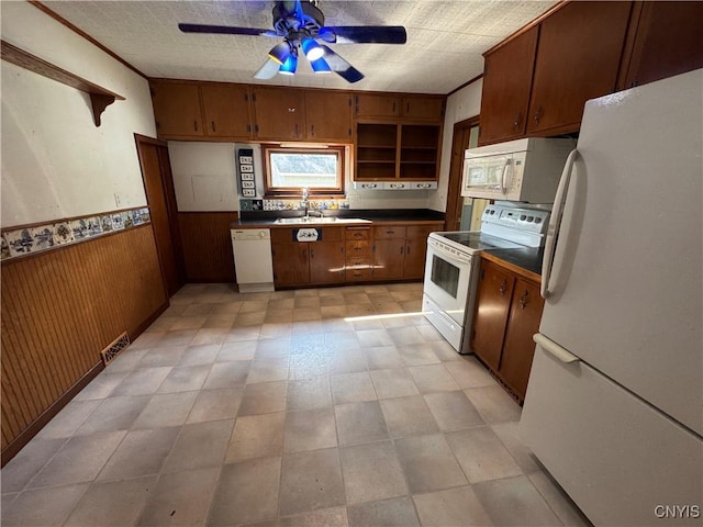 410 W Elm St, Oneida, NY 13421 - kitchen featuring white appliances, a ceiling fan, wooden walls, dark countertops, and a wainscoted wall
