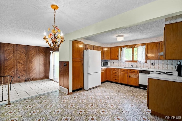 270 N French Rd, Amherst, NY 14228 - kitchen featuring white appliances, a textured ceiling, a chandelier, brown cabinets, and light countertops