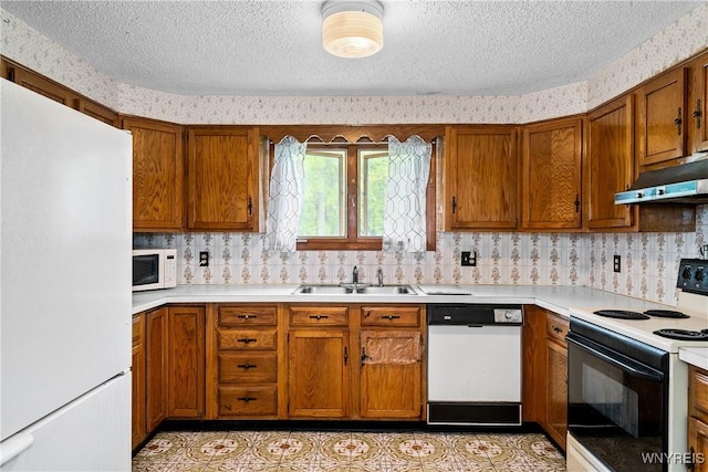 270 N French Rd, Amherst, NY 14228 - kitchen featuring white appliances, under cabinet range hood, a textured ceiling, brown cabinetry, and light countertops