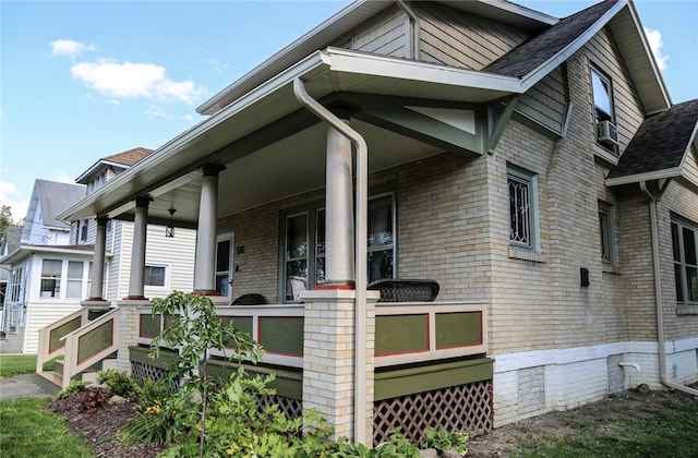 561 W Washington Ave, Elmira City, NY 14901 - view of side of property featuring covered porch, brick siding, and roof with shingles