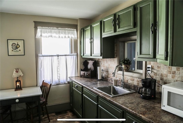 561 W Washington Ave, Elmira City, NY 14901 - kitchen with green cabinets, white microwave, decorative backsplash, dark countertops, and dark wood-type flooring