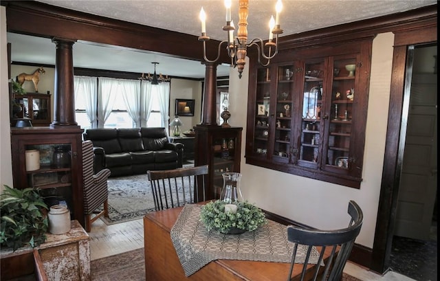 561 W Washington Ave, Elmira City, NY 14901 - dining space with a chandelier, wood finished floors, crown molding, decorative columns, and a textured ceiling