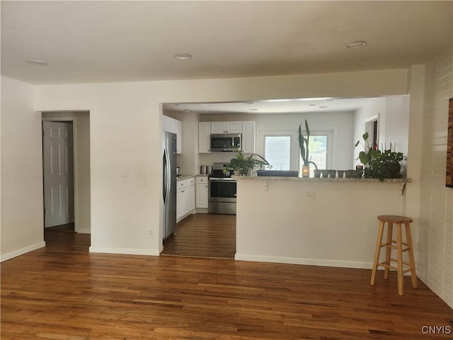 219 Camillus Dr, Camillus, NY 13031 - kitchen with stainless steel appliances, a kitchen bar, a peninsula, light stone countertops, and recessed lighting