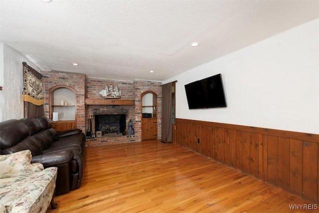 131 Shady Grove Dr, Amherst, NY 14051 - living area featuring light wood-style flooring, wainscoting, a textured ceiling, a fireplace, and wooden walls