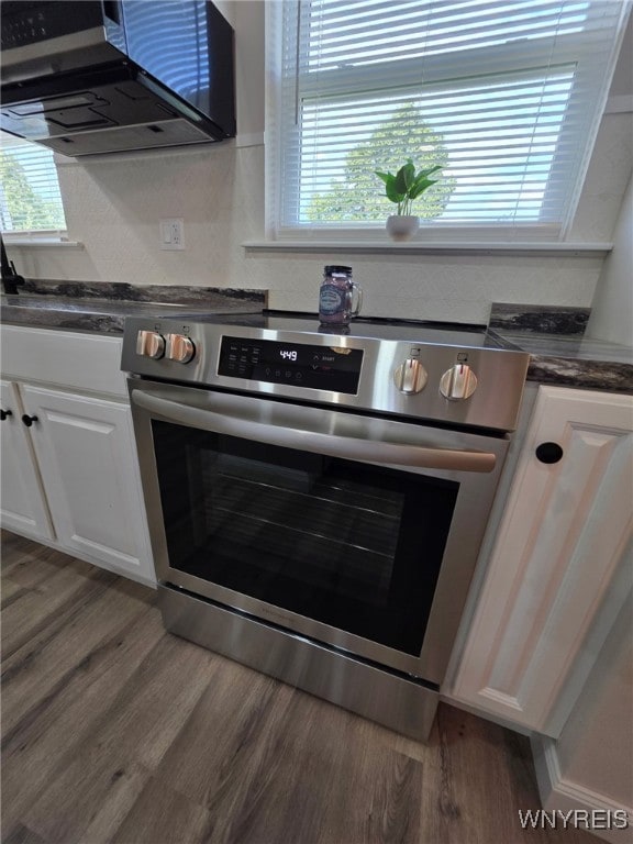 24 Wenonah, Tonawanda, NY 14150 - kitchen with stainless steel range with electric stovetop, dark countertops, white cabinets, and wood finished floors