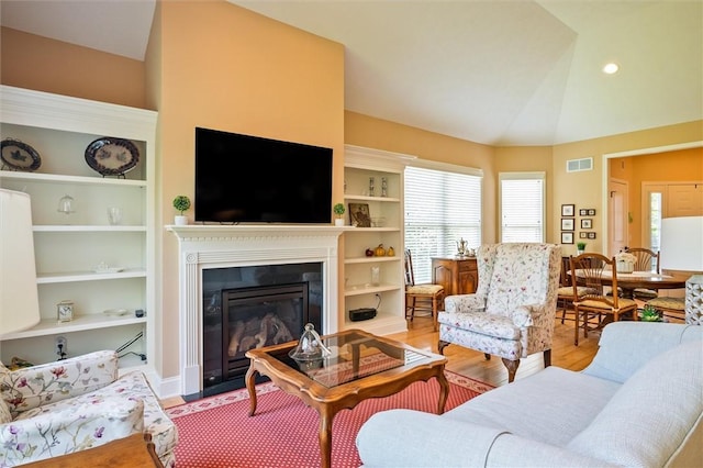 1100 Yorkshire Way, Victor, NY 14564 - living area with a glass covered fireplace, wood finished floors, built in shelves, and vaulted ceiling