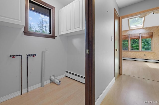 1575 Overhead Rd, Evans, NY 14047 - laundry area featuring a baseboard heating unit, baseboard heating, cabinet space, and light wood-type flooring