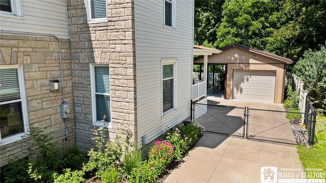 49 Day St, Pomfret, NY 14063 - view of home's exterior featuring stone siding, an outdoor structure, a gate, a detached garage, and driveway