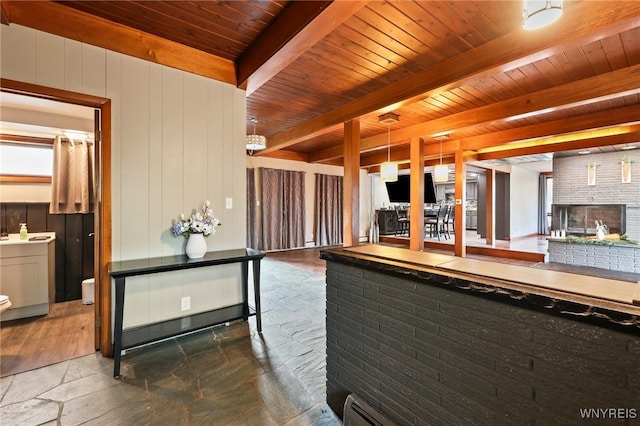 722 College Ter, Niagara Falls, NY 14305 - kitchen with a wood ceiling with exposed beams, stone tile flooring, open floor plan, a brick fireplace, and wooden walls
