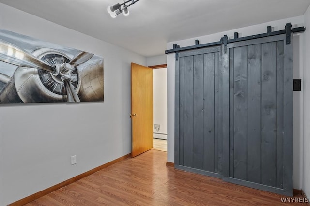 722 College Ter, Niagara Falls, NY 14305 - unfurnished bedroom featuring a barn door and wood finished floors