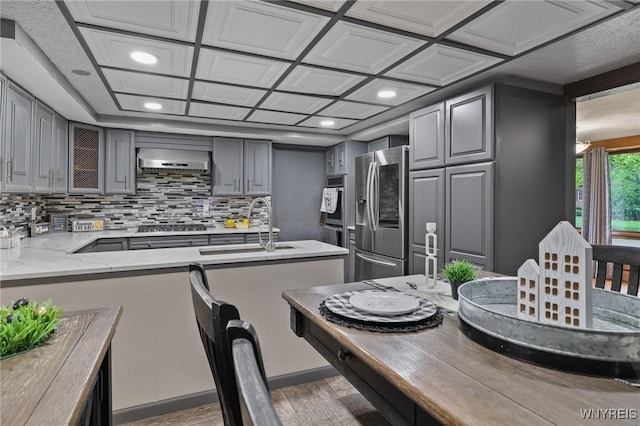 722 College Ter, Niagara Falls, NY 14305 - kitchen featuring gray cabinetry, stainless steel appliances, range hood, wood finished floors, and decorative backsplash