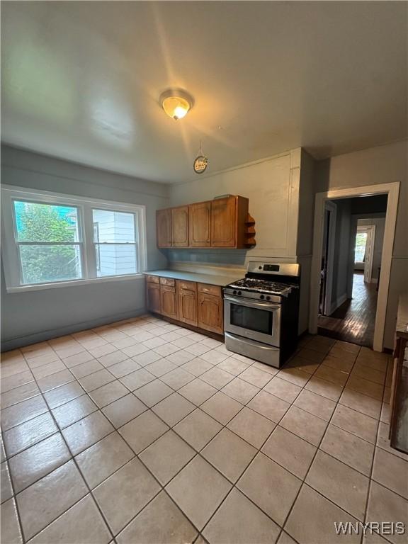 24 Northrup Pl, Buffalo, NY 14214 - kitchen featuring gas stove, light tile patterned floors, brown cabinetry, and light countertops