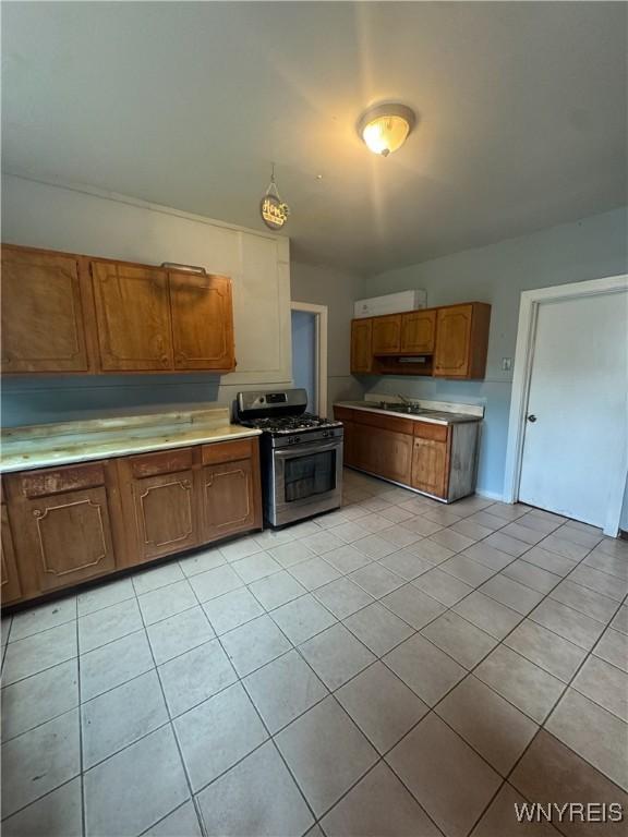 24 Northrup Pl, Buffalo, NY 14214 - kitchen featuring gas stove, light tile patterned flooring, light countertops, and brown cabinets