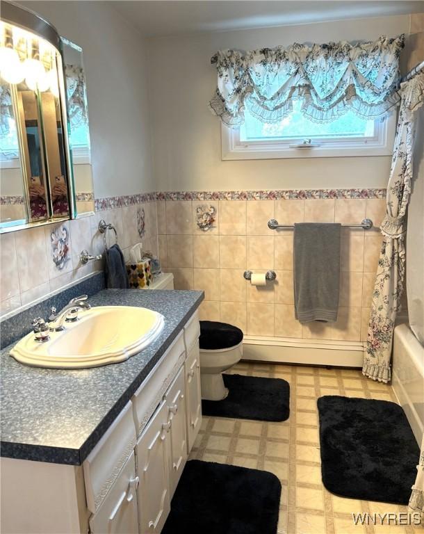 80 Jeffrey Dr, Amherst, NY 14228 - bathroom featuring baseboard heating, plenty of natural light, vanity, tile walls, and shower / tub combo with curtain